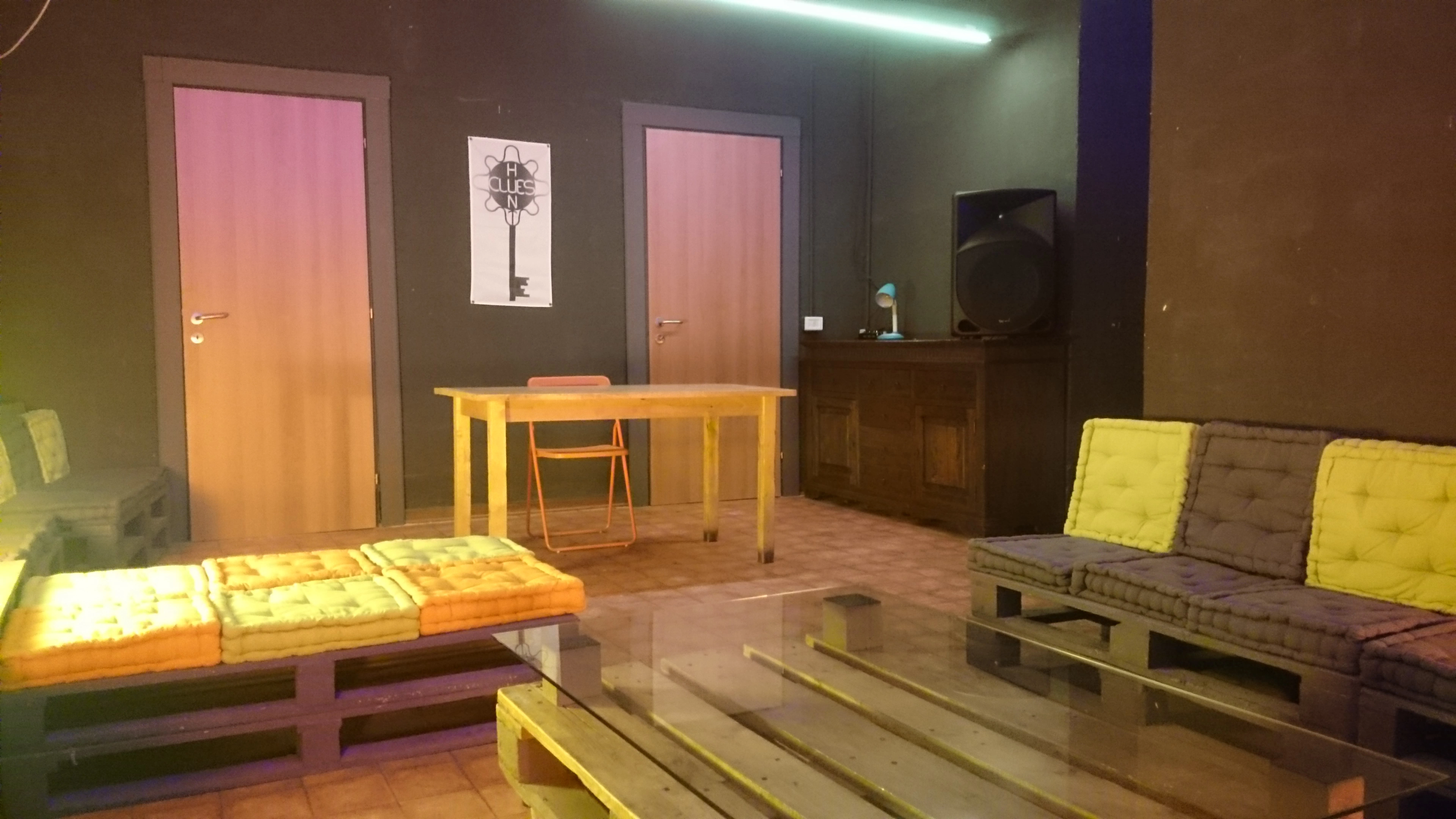 Sala affitto per feste di laurea a Milano: spazio esclusivo Clues Hunt con sedute in pallet e atmosfera ricercata.
